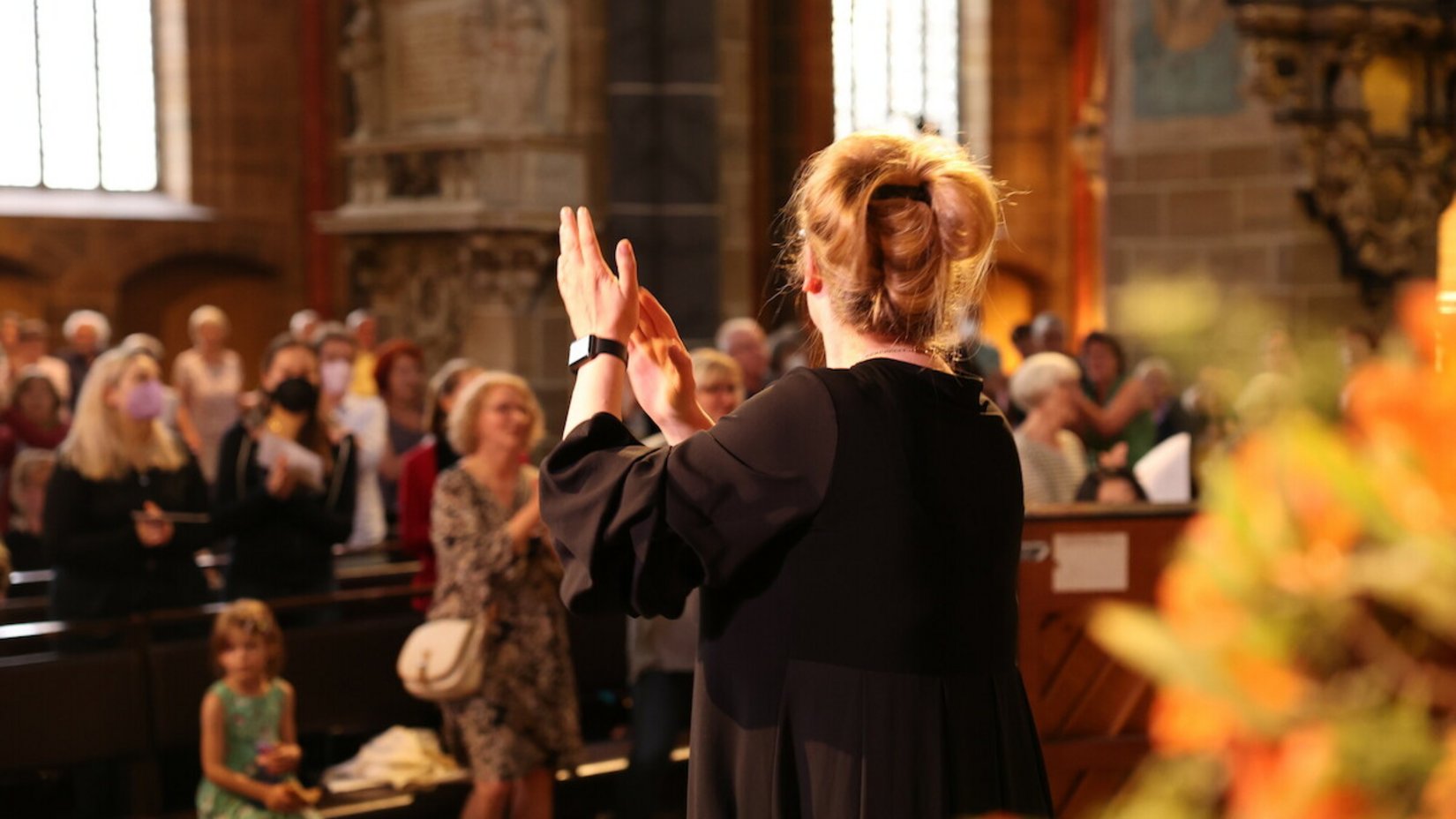 Frau dirigiert Gemeindegesang in der Kirche