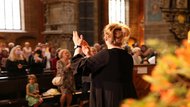 Frau dirigiert Gemeindegesang in der Kirche